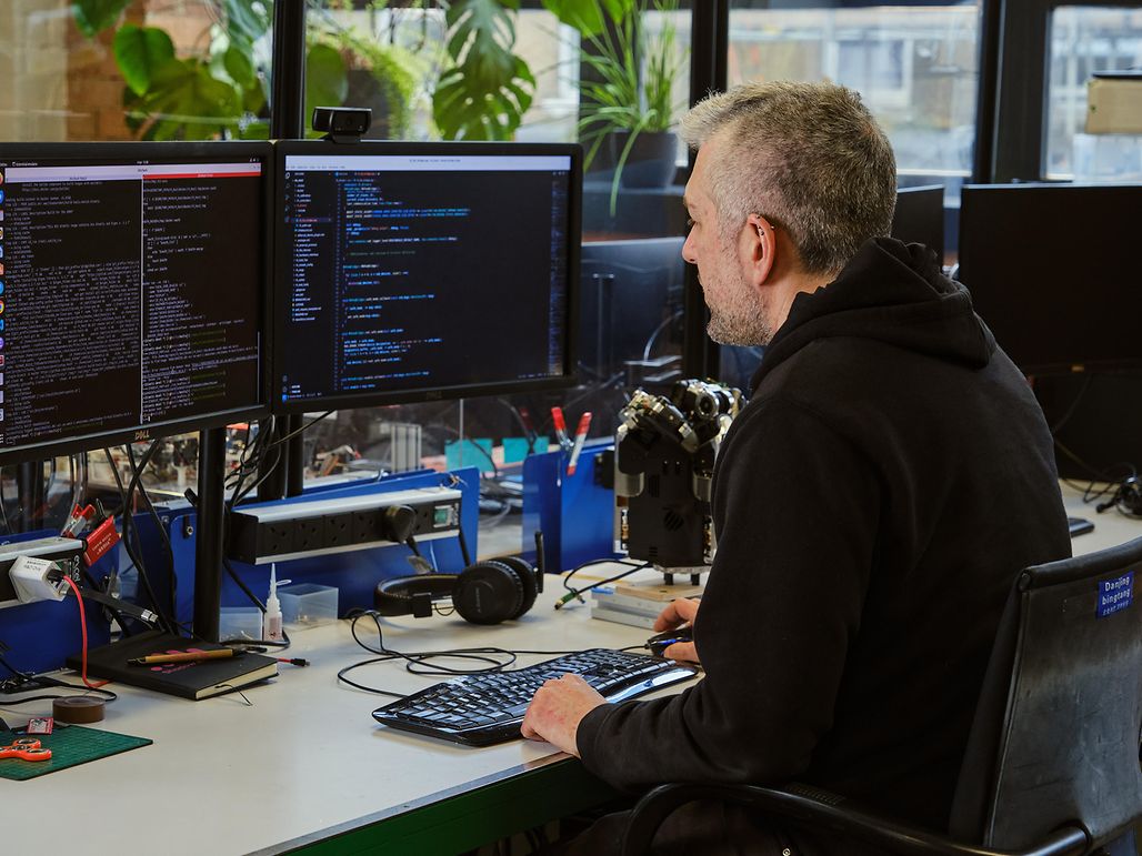 A man at a desk with two monitors, concentrating on his programming tasks.