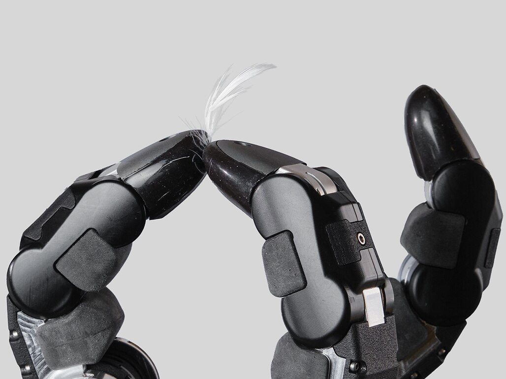 A robotic hand holding a feather, showcasing advanced technology and precision in design.